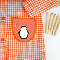 bolsillo del babi de botones naranja con el diseño de un pingüino