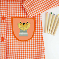 bolsillo del babi de botones naranja con el diseño de un león